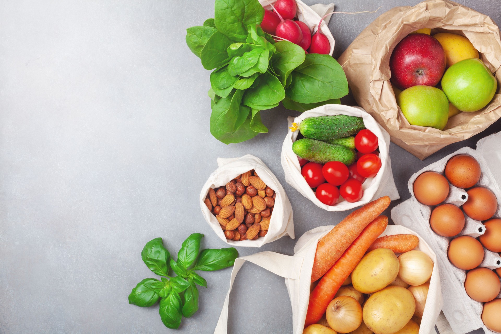 Fresh vegetables and fruits in natural eco friendly cotton and paper bags top view. Zero waste food shopping and plastic free concept.
